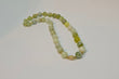 Beaded bracelet or tasbeeh with green serpentine jade beads and gold plated accents on a light gray background